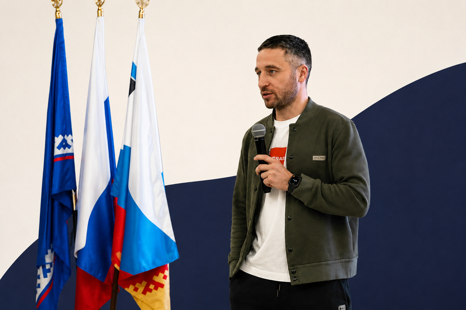 Максим Недельский выступает перед флагами на деловом мероприятии